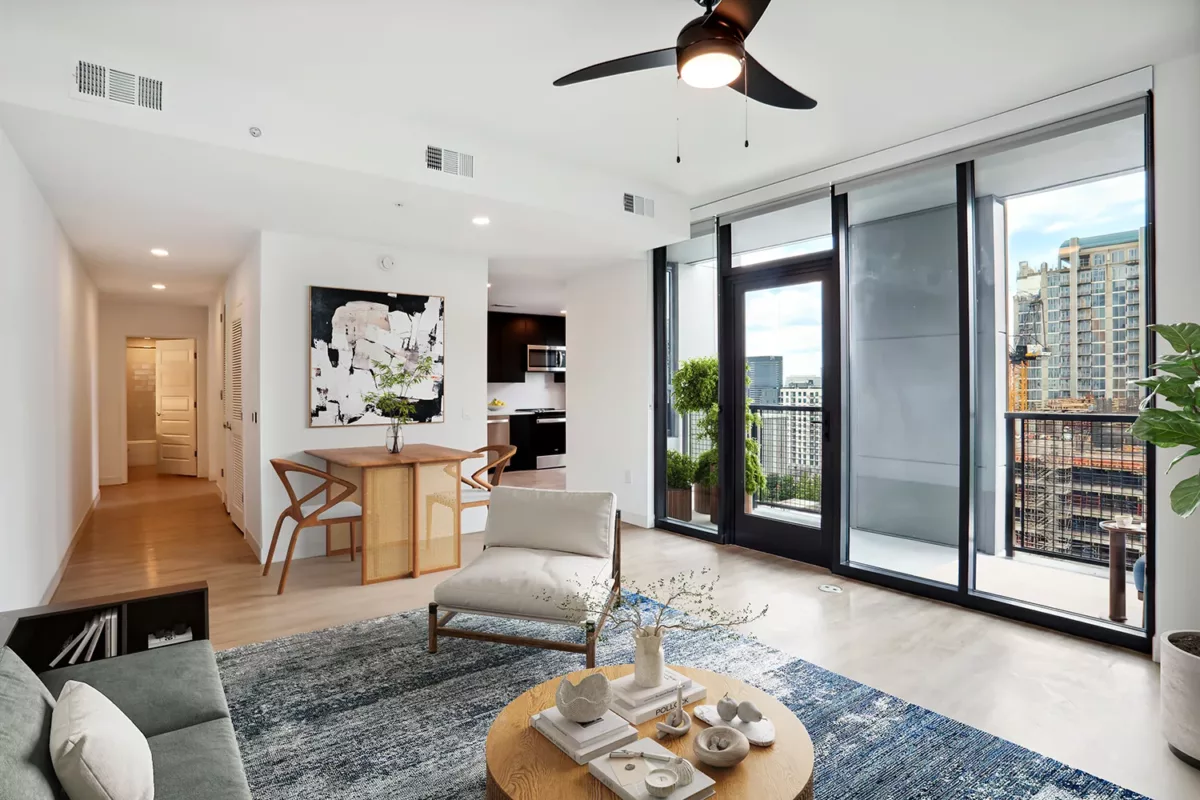 Open living space with a dining area, balcony with city view, and contemporary decor, and a ceiling fan.