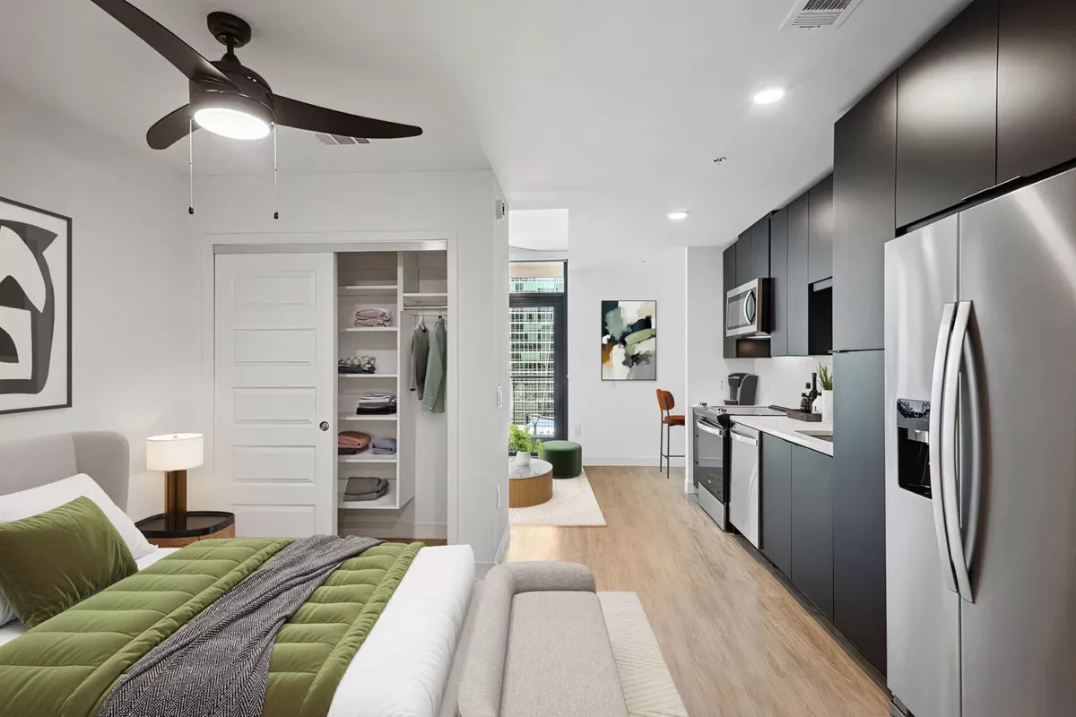 Studio apartment layout with a bedroom, closet, kitchen, and small dining area, featuring neutral tones and modern decor.