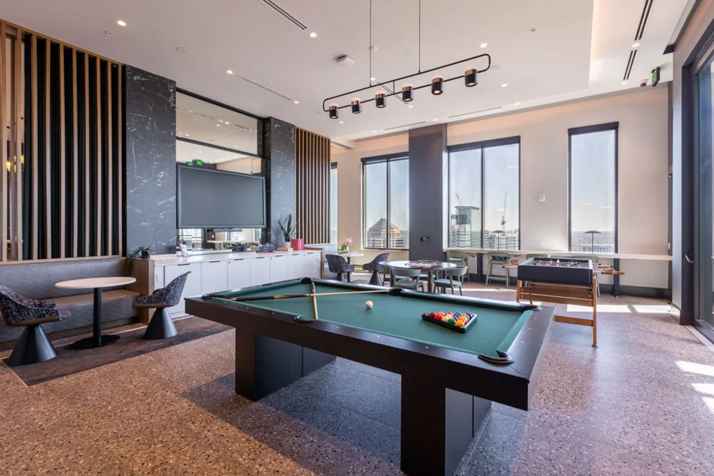 Recreation room with a pool table, foosball, chess, and cozy seating areas in a bright, modern space.