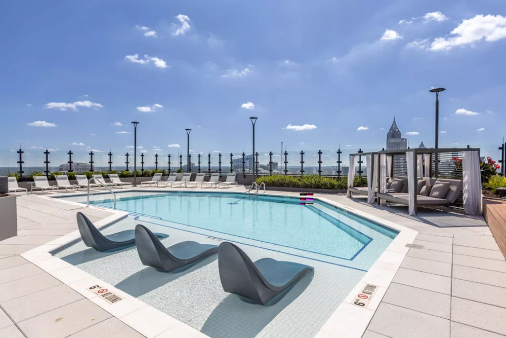 Rooftop pool with lounge chairs, cabanas, and city views.